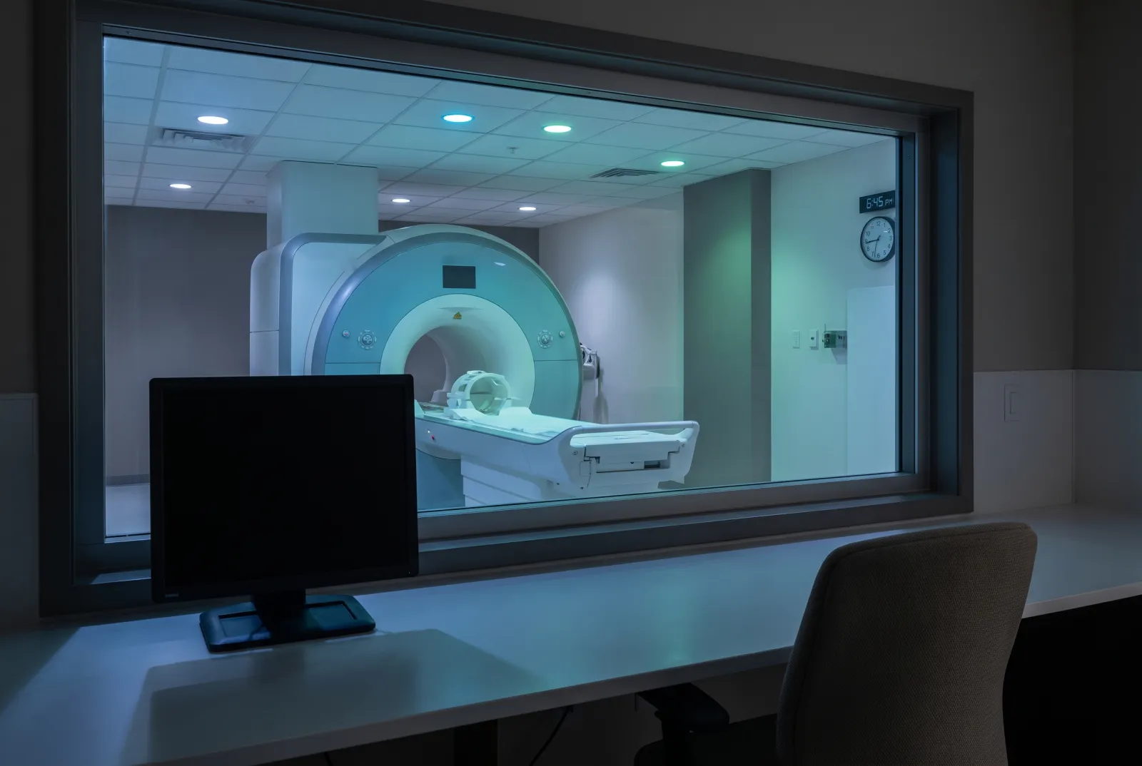 AI-generated illustration of an empty MRI scanner room seen through a control room window